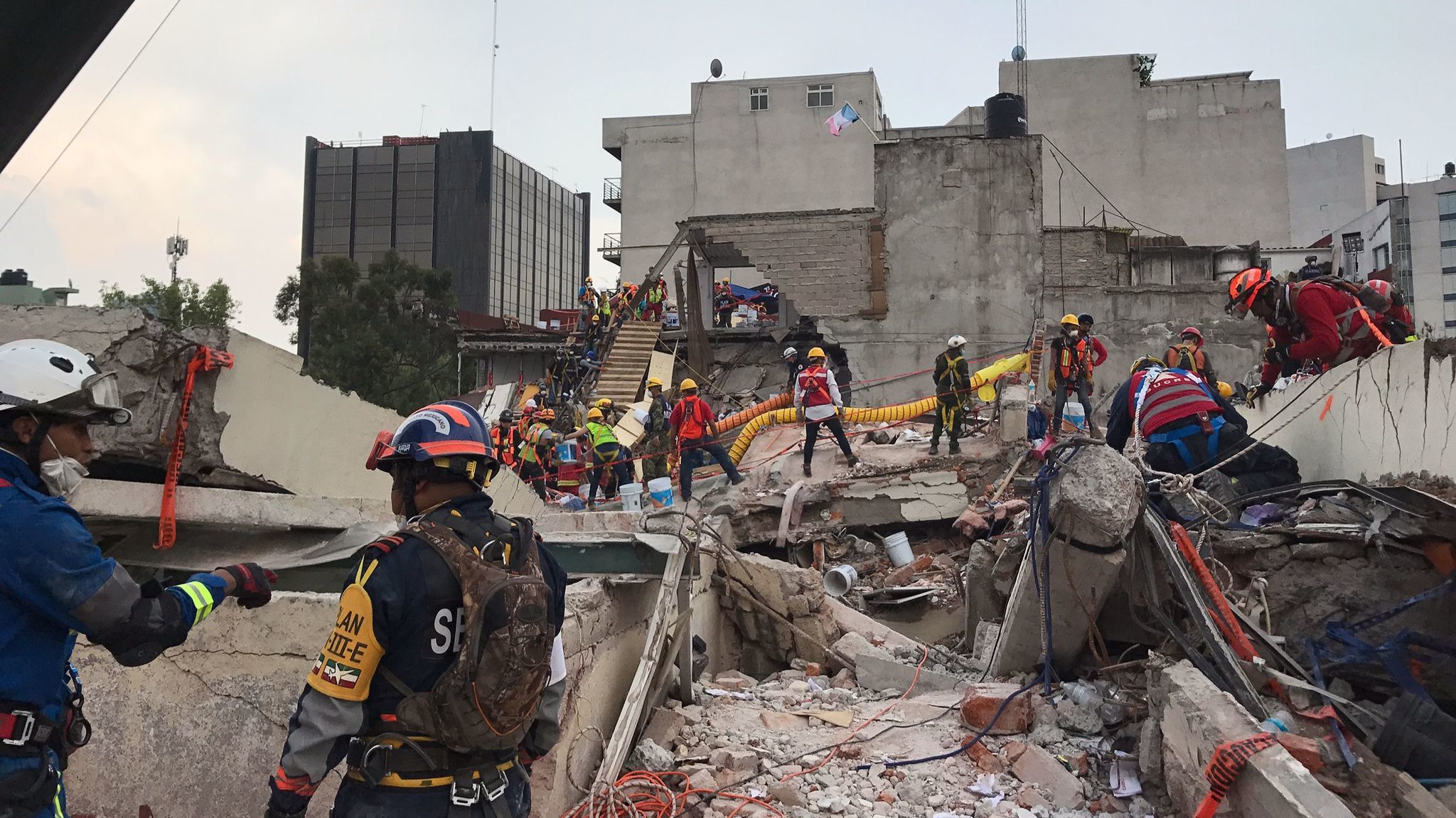 Emergency workers continue the recovery effort from the roof of the office building at Avenida Alvaro Obregon 286.
