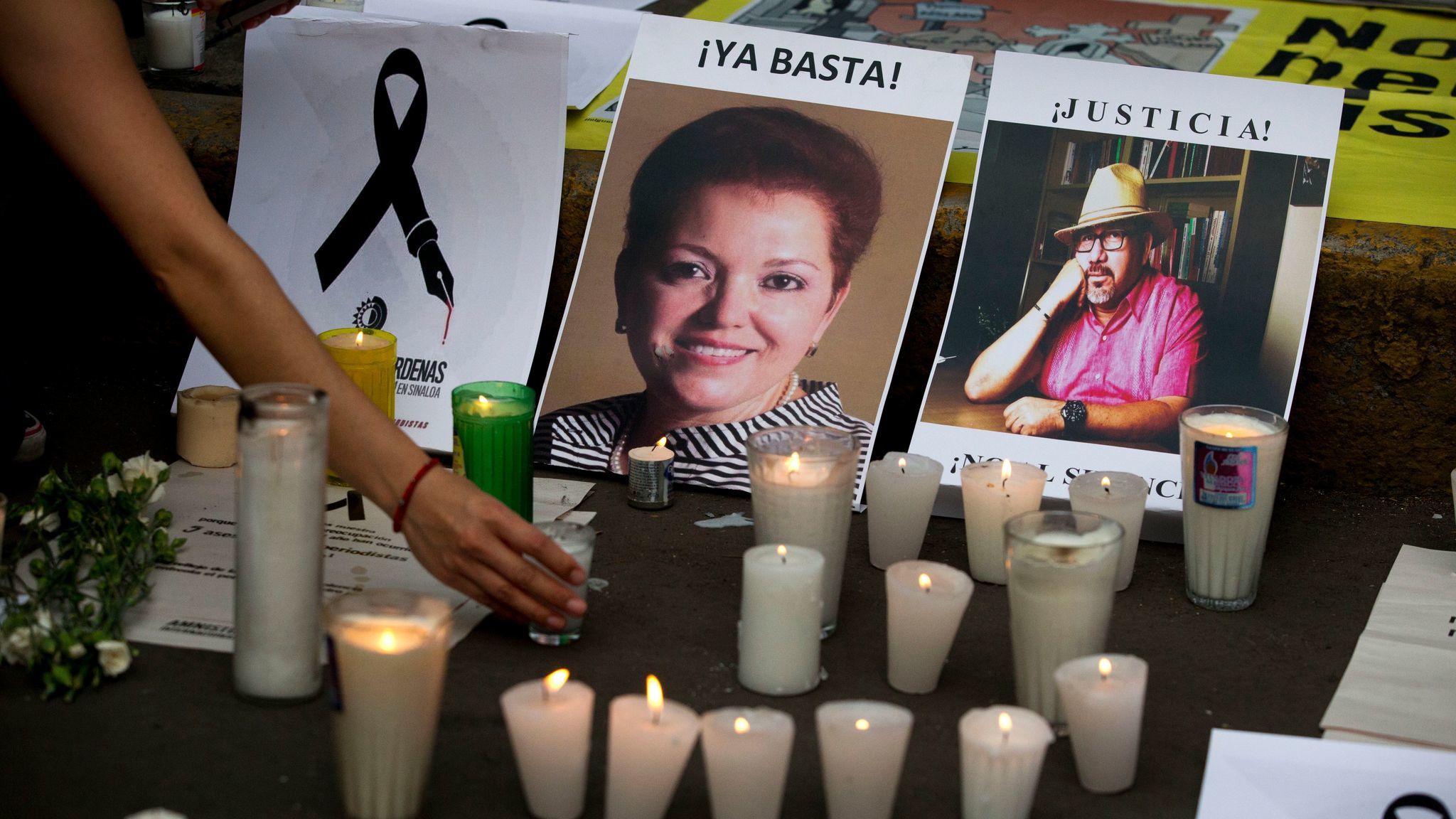 FILE - In this May 16, 2017 file photo, a woman places a candle in front of pictures of murdered jou
