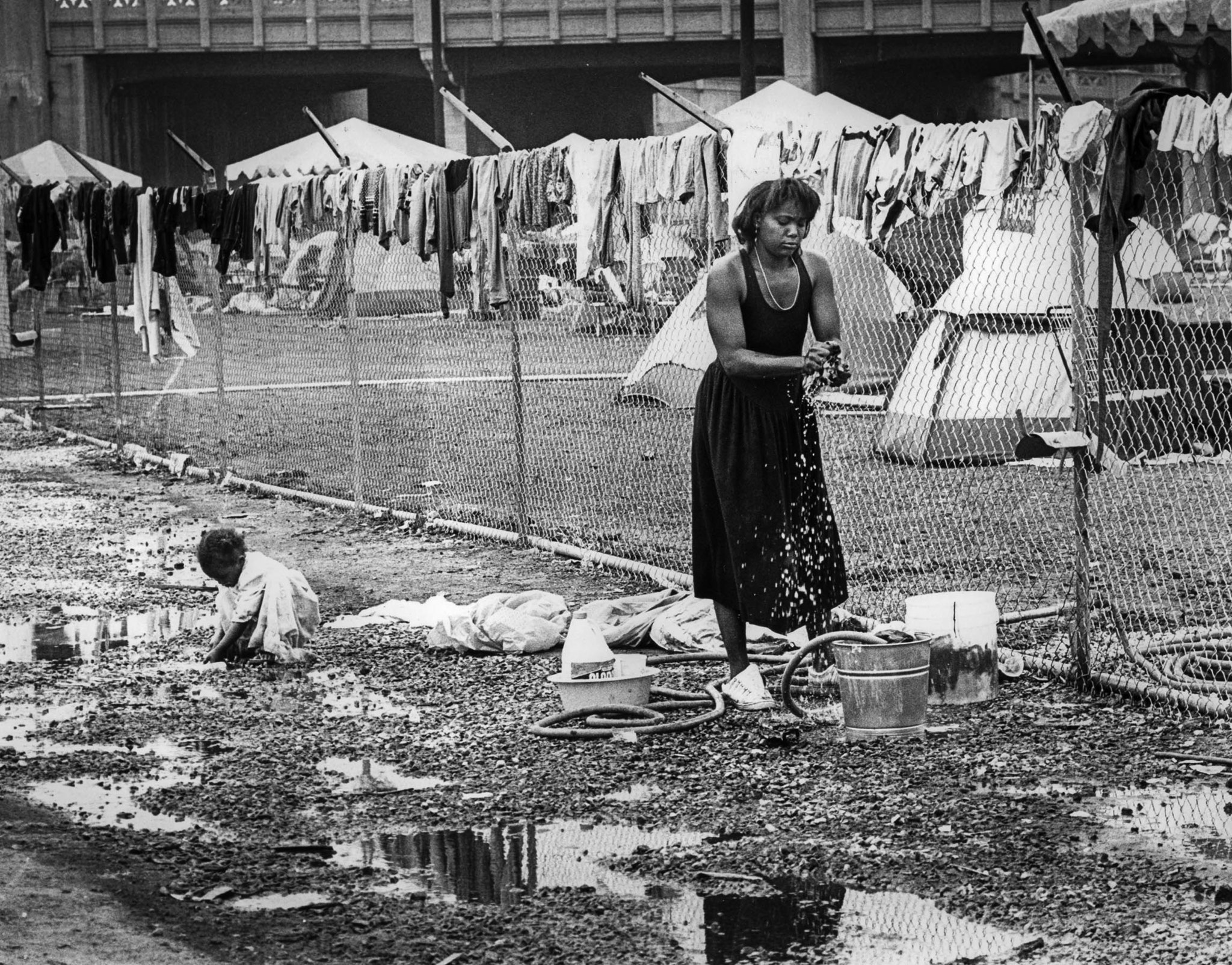 July 15, 1987: Carolyn Blue hangs her wash on fence at Urban Campground, while daughter Shameka, 3,