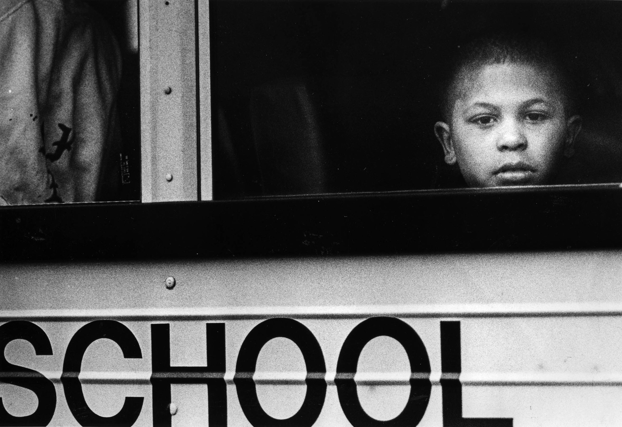 Aug. 14, 1987: A child peers out of school bus window as she waits for others from the Urban Campgro