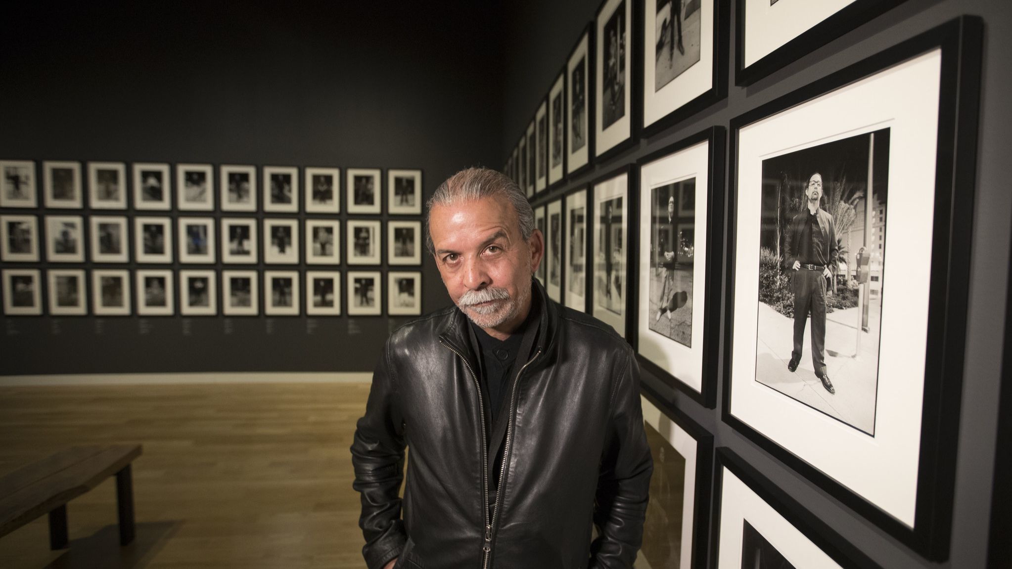 Photographer Harry Gamboa Jr. stands amid his portraits
