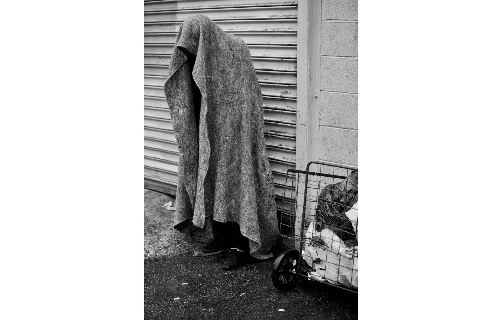 LOS ANGELES, CA - DECEMBER 2, 2014: A person stands beneath a blanket in the rain trying to keep dry
