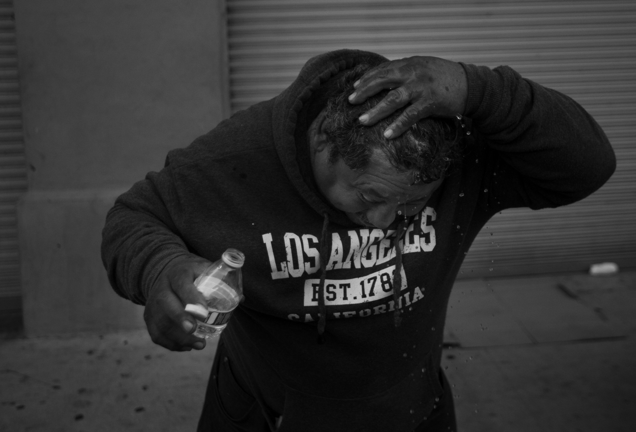 LONG BEACH, CA November 15, 2017: Oscar Gonzalez, 50, showers using a small bottle of water before h