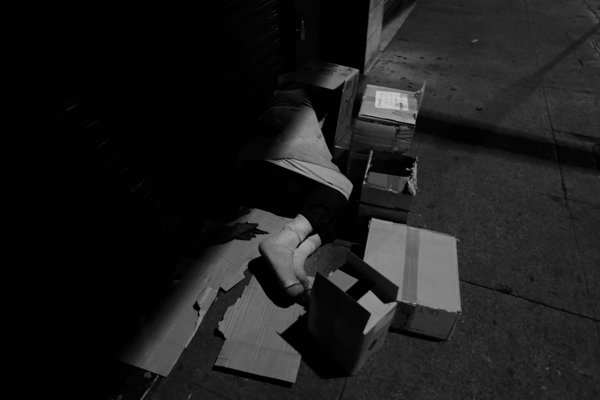 LOS ANGELES, CA February 2, 2018: A person sleeps on a piece of card board, surrounded by boxes o