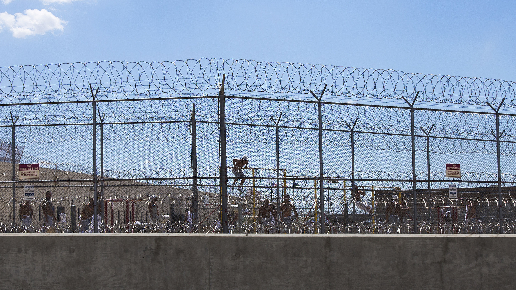 ADELANTO, CA - JULY 7, 2014: Detainees work out in the yard behind double fencing and barbed wire at