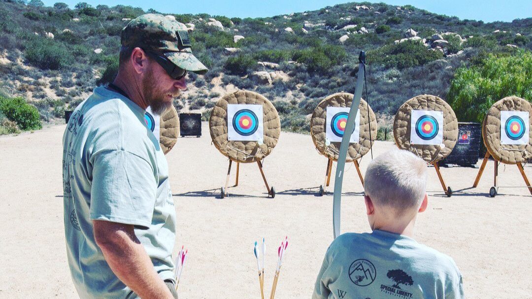 Veteran Mike Brown guides Alex Turpen, one of The Special Liberty Project’s Gold Star children, at the archery range at Lake Poway.
