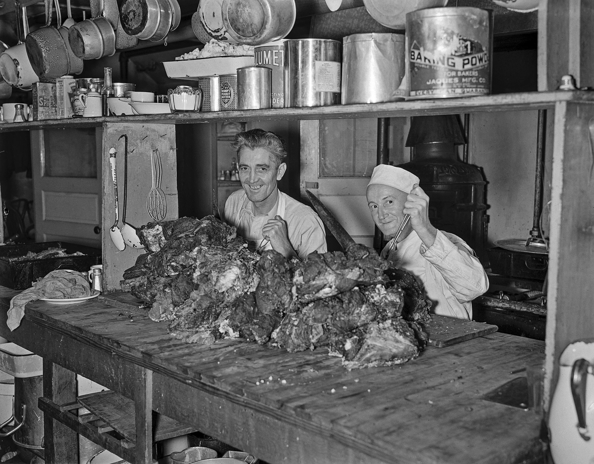 Nov. 26, 1936: Bob Boyd and Chef George Arnold in a kitchen cutting beef for Thanksgiving dinner at